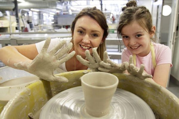 Students learn to make a pot from clay on a wheel